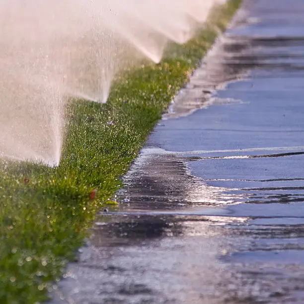 Photo of Irrigator wasting water while watering the grass