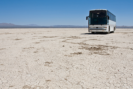 A bus parked in the middle of the desert.