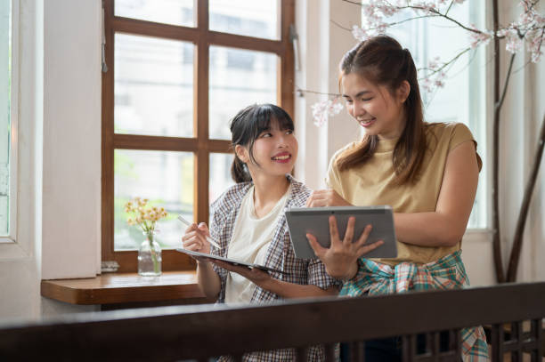 istock Two beautiful Asian women are discussing project plans while working remotely at a cafe together. 1728816264