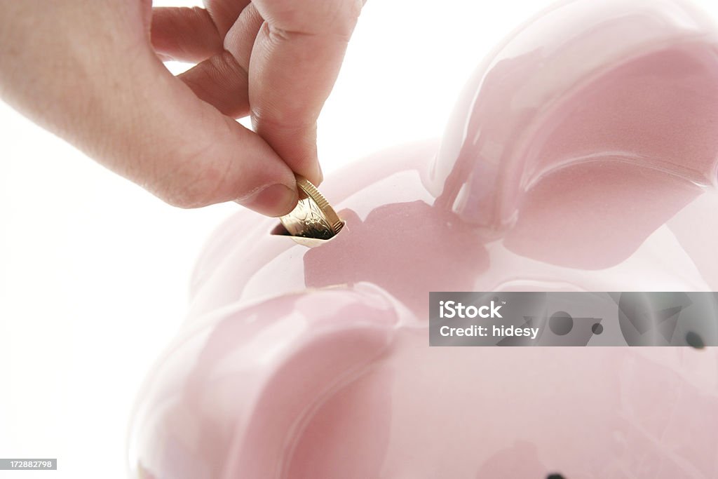Savings Hand putting coin in piggybank.  Closeup Banking Stock Photo