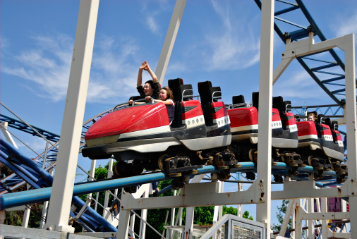 Children riding a rollercoaster at an amusement park.