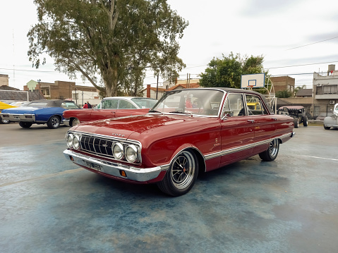 Lanús, Argentina - Sept 24, 2023: Old red shiny Ford Falcon Futura XP 221 sedan compact family car early 1970s in a park. Vinyl roof. Classic car show