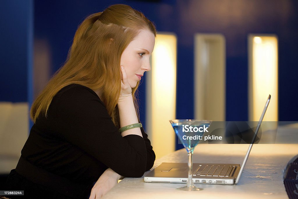 Woman with laptop at a bar Woman sits at a bar with a martini and her laptop Cocktail Stock Photo