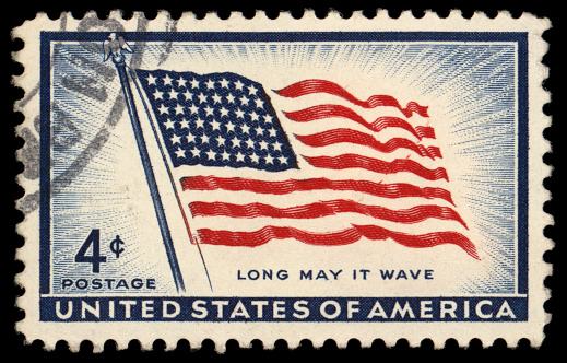 US Flag waving at a distance, behind the leaves of an oak tree. Retro postcard look.