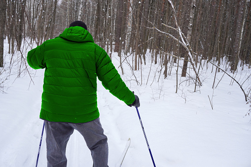 man 50 years old skiing in the forest in winter