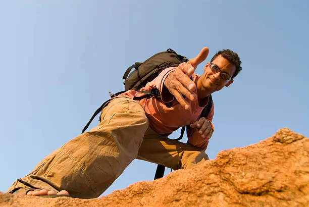 Man standing on rock offering a hand up