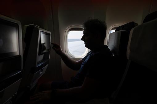 Indian man using inflight entertainment on a flight to Paris