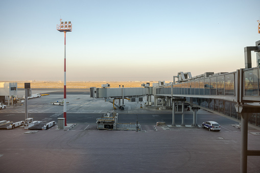 View from airport departure area of the passenger boarding bridge on airport tarmac awaiting arrival of airplane.