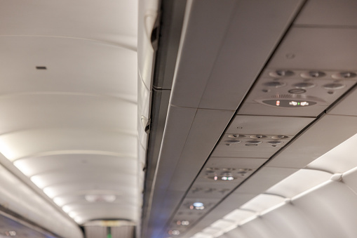 Inside a commercial airplane in the economy class. Airplane aisle visible. Shallow DOF.