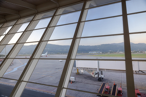 View from airport departure area of the passenger boarding bridge on airport tarmac awaiting arrival of airplane.