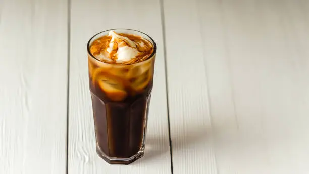 Iced coffee in a glass placed on a white wooden floor