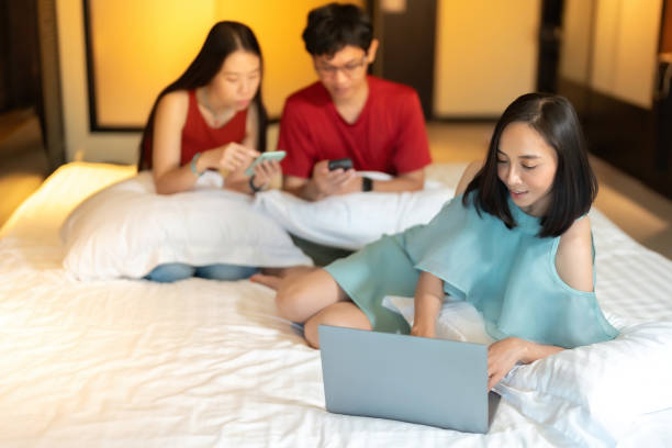 Top view of Asian businesswoman leader Smiling and typing with a laptop There is a co-worker behind him working with a smartphone. Wear a red shirt and a light green dress. In the hotel bedroom vista superior de la líder empresaria asiática sonriendo y escribiendo con una computadora portátil hay un compañero de trabajo detrás de él trabajando con un teléfono inteligente. usa una camisa roja y un vestido verde claro. en la habitación del