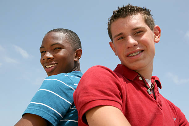 Two teenagers back to back and smiling.
