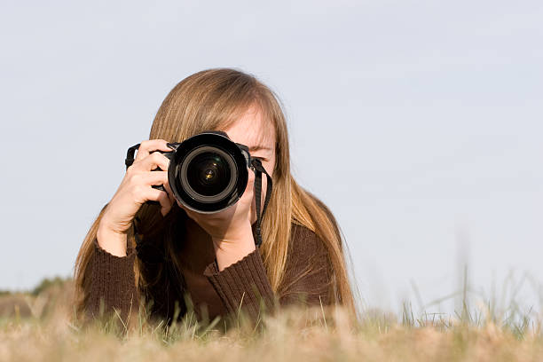 istock Female Photographer Lying on Ground Outdoors in Action Holding Camera 172895394