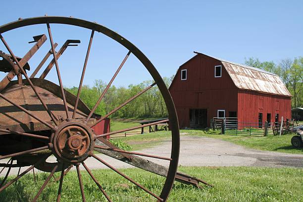 Farmer's antique wood wagon wheel laying upon hay bales.