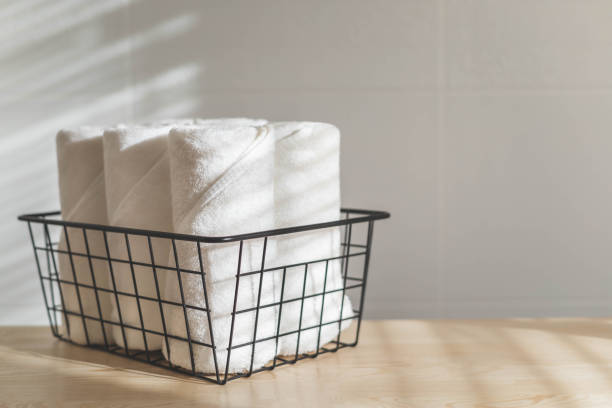 istock Fresh white towels rolled fluffy fabric spa textile stack in metallic basket wooden sunny tabletop 1728968865