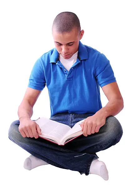 A teenager sits cross-legged with a book in his lap.