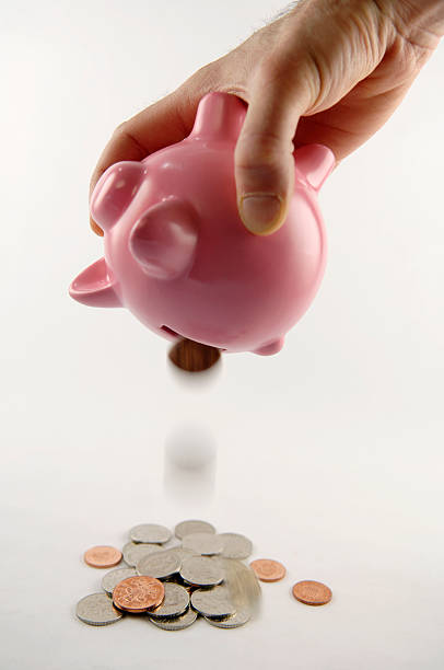 piggy bank selective focus image of piggy bank being emptied out british falling pounds stock pictures, royalty-free photos & images