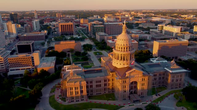 Downtown Austin, Texas State Capital Building, Aerial Drone Shot Circling Dome with Goddess of Liberty Statue on Top with Views of The University of Texas at Austin Campus, Skyline at Sunset in 4K.