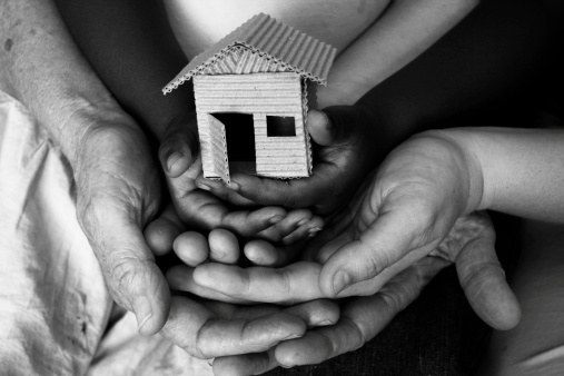 three layers of hands supporting a home (shot in b/w)