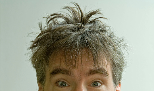 Wide eyed male with crazy bed head on white background