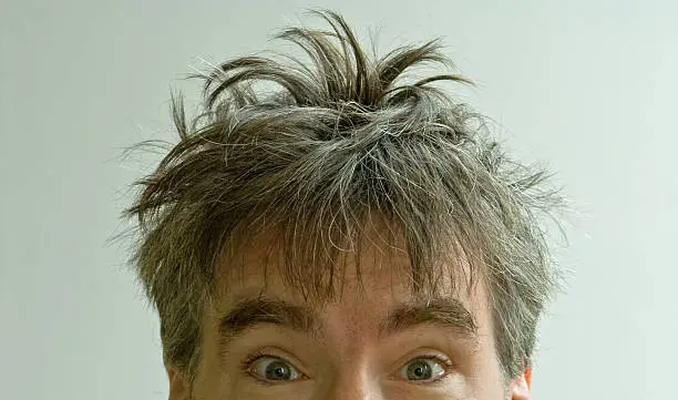 Photo of Wide eyed male with crazy bed head on white background