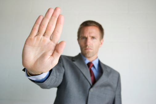 Businessman holds out a hand with a stern expression on his face