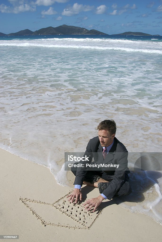 Uomo d'affari seduto su una spiaggia tropicale di sabbia, lavorando su computer - Foto stock royalty-free di Affari