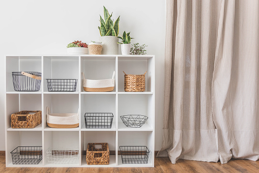 White stylish shelf in scandi style. Storage baskets. Japanese method organizer boxes set. Closet organizing concept.