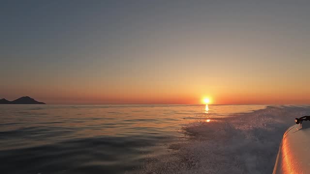 Beautiful golden sunset on the horizon over sea as seen from moving navigating dinghy boatBeautiful golden sunset on the horizon over sea as seen from moving navigating dinghy boat
