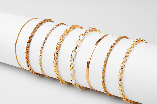 Set of golden bracelets on display on white background close up