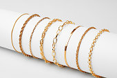 Set of golden bracelets on display on white background