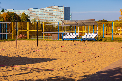 An empty sports volleyball court in a city park near a pond