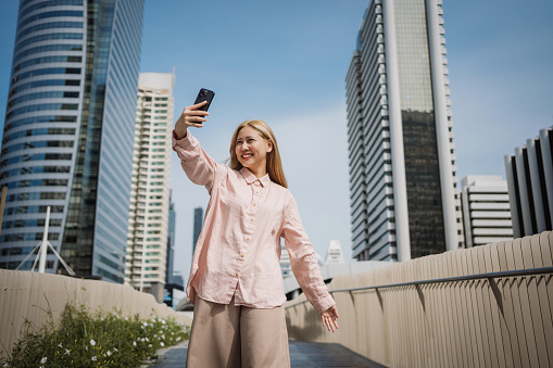 Young enthusiastic woman is taking selfies in the urban city.