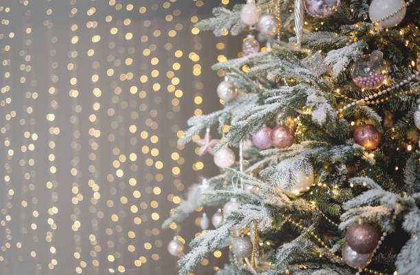 istock Festive decorated Christmas tree fluffy branches covered by snow and bright golden shiny garland 1729017684