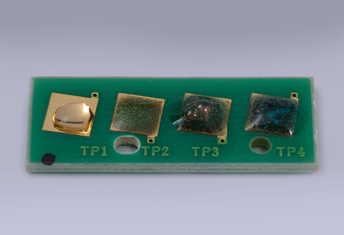 Drops of aqua regia at different concentrations react with gold plated contacts on a printed circuit board. From left: 10 K, 14K, 18K, 22K solutions of test kit acid show the contacts are between 10k and 14K.