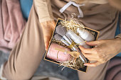 Female hands holding Christmas craft gift box full of beauty presents for skin, body and face care