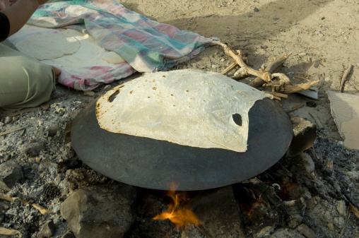 A Bedouin woman baking pita bread on a stove in the Arava desert Israel