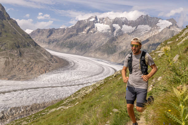 istock Trail runner ascends alpine path in Swiss mountain landscape, Glacier in the background 1729019980