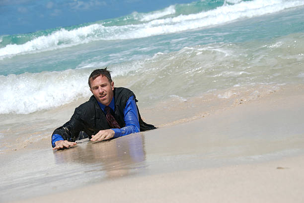 naufrago uomo d'affari lavaggi a terra - stranded beached beach businessman foto e immagini stock