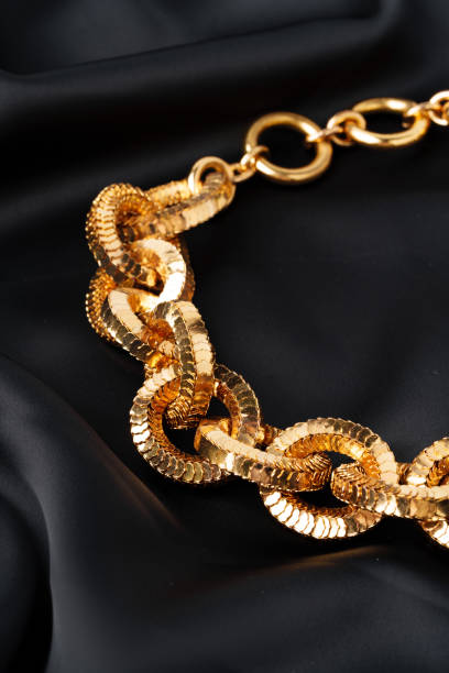 istock Gold chain on black silk fabric background 1729024145