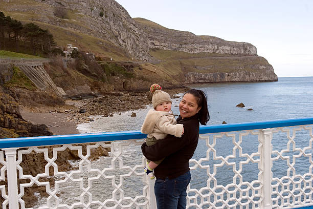 Mother and baby at the seaside Asian mother and baby son on the pier at Llandudno, Wales. fleece photos stock pictures, royalty-free photos & images