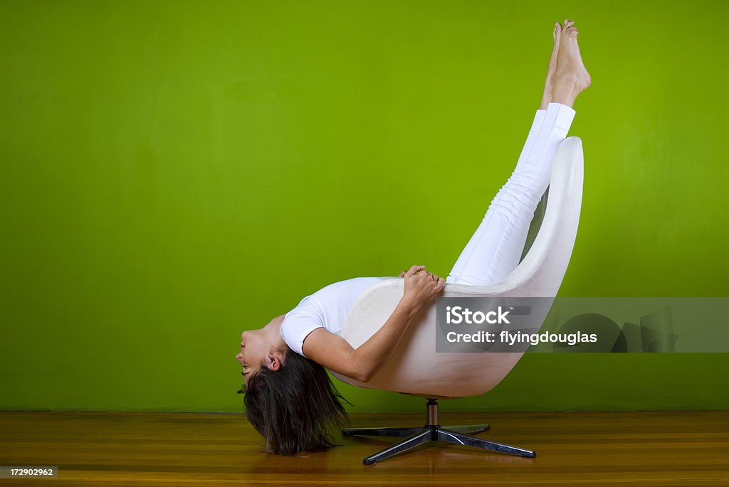 Flying Upside down A girl in all white sits upside down in a Danish design Mid Century egg chair. Adult Stock Photo