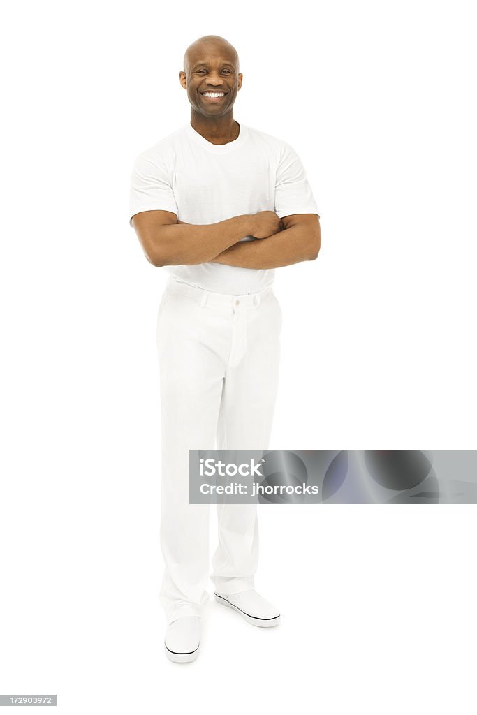 Smiling Confident African American Man in White Photo of a bald African American man in white shirt, white pants and white shoes, standing with arms folded against a white backdrop. Men Stock Photo