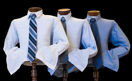 Men's dress shirts and ties on display, against a black background.