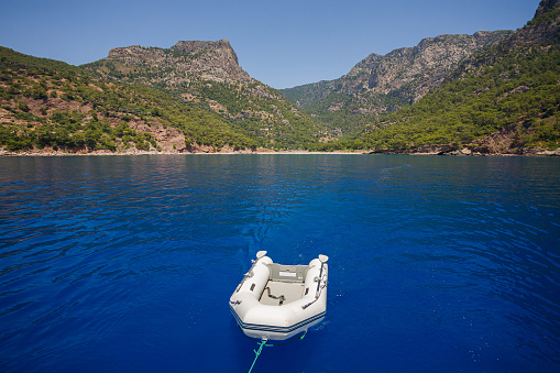 A plastic boat tied behind another boat.