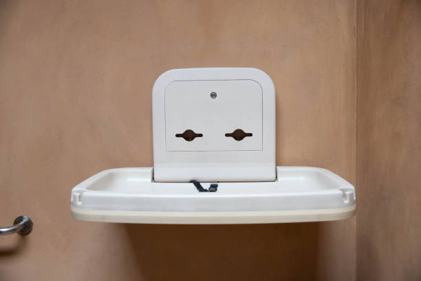 a diaper table or table changing station, plastic furniture designed for changing diapers and dressing infants on the brown wall in the public restroom.