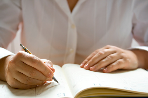 Businesswoman writing in personal organizer