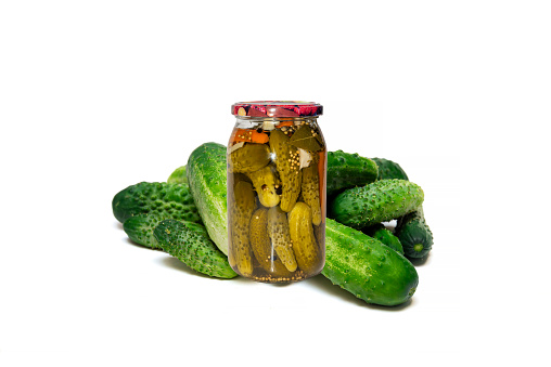 Fresh cucumbers and a jar of pickles on a white background, homemade cucumbers