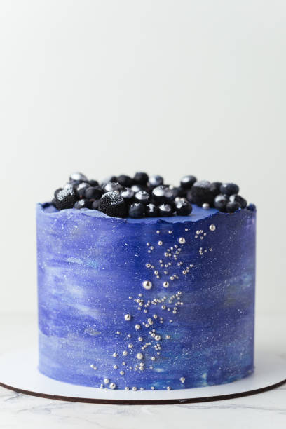 istock Birthday cake with blue cream cheese frosting decorated with blueberries covered with silver kandurin. Cosmic cake or space themed cake on the white background. 1729082103